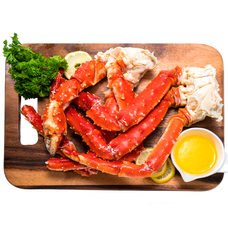 four large red king crab legs on a cutting board with a container of melted butter